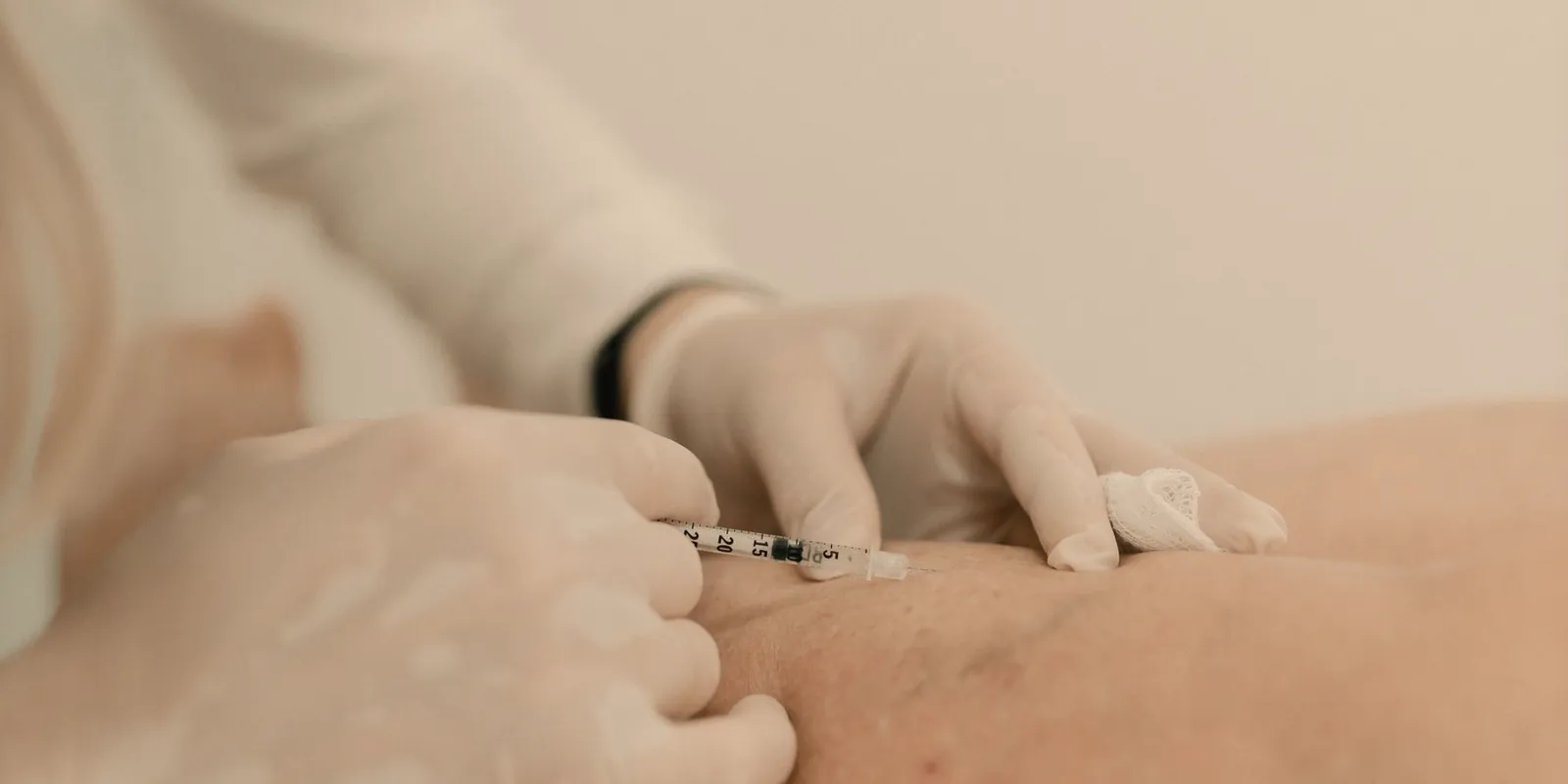 Profesional con guantes aplicando una inyección en la pierna